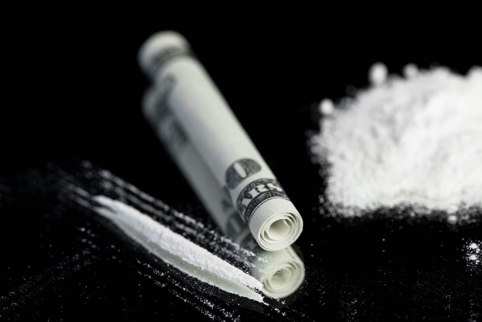 rolled up U.S. paper money and white powder