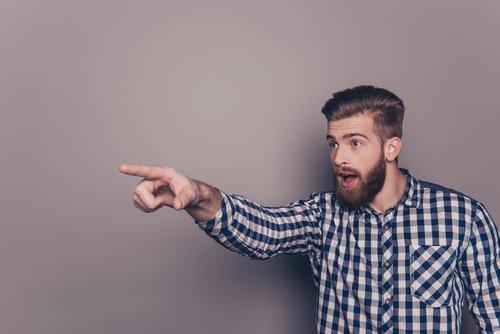 young bearded man pointing finger at something or someone
