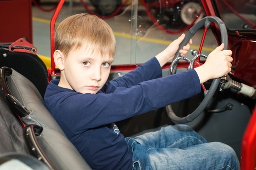 A young boy behind the wheel of an automobile.