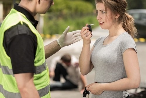 police officer administering a PAS test to a young woman after a traffic accident