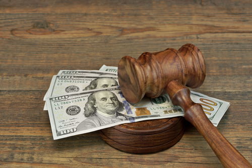 stack of 100 dollar bills under a judge's gavel