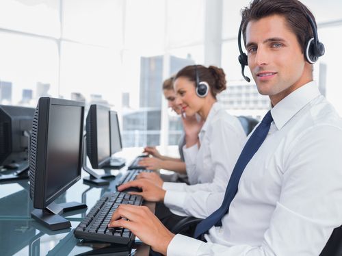 row of 3 receptionists at computer stations with headsets