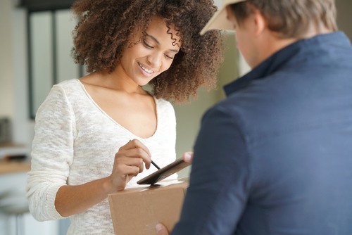 Woman signing for a package from a delivery man