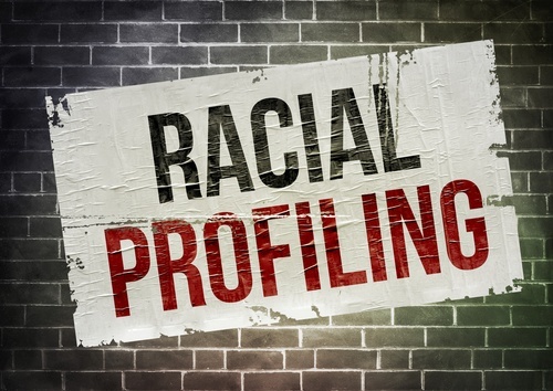 Sign that says "racial profiling" on a brick wall