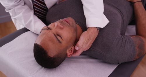 chiropractor adjusting head and neck of male patient