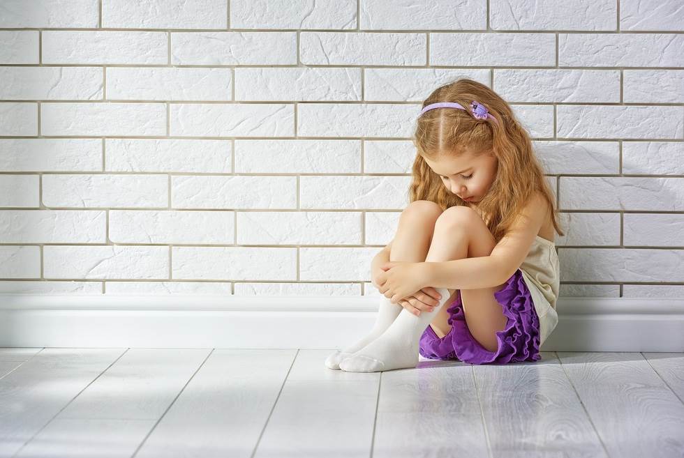 Young child sitting with face down