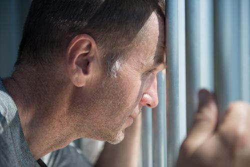 recluso mirando desde una celda de prisión - una condena por el Código de Negocios y Profesiones 12024.1 BPC conlleva una pena de hasta 6 meses en la cárcel
