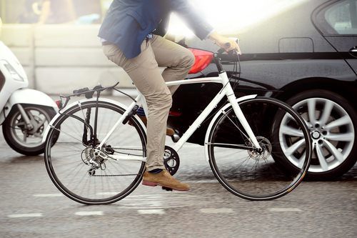 ciclista en carril bici paralelo a un coche - El Código de Vehículos 21200 VC impone a los ciclistas el mismo deber de seguir las leyes de tráfico que se impone a los conductores de vehículos