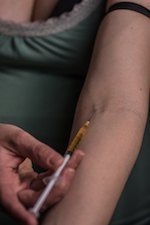 Person shooting up heroin in arm
