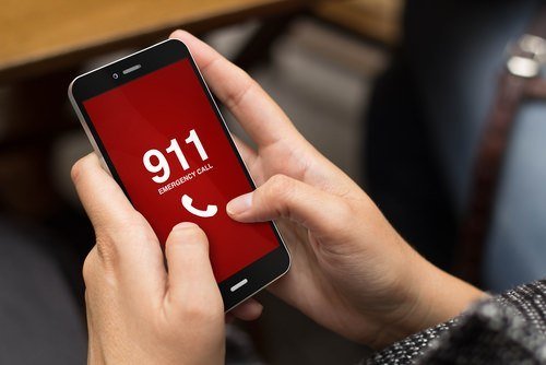 Hands holding mobile phone calling 911