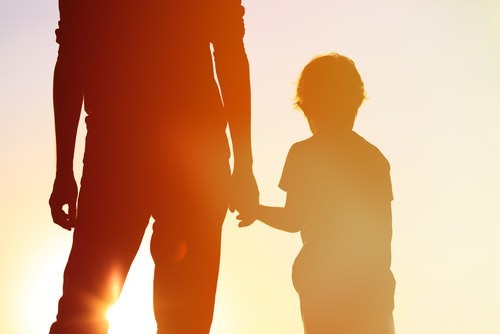 Adulto sosteniendo la mano de un niño pequeño - se invoca el compromiso de una reclamación de un menor para acuerdos monetarios en los que el menor es beneficiario