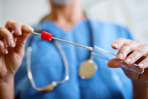 nurse placing mouth swab in test tube