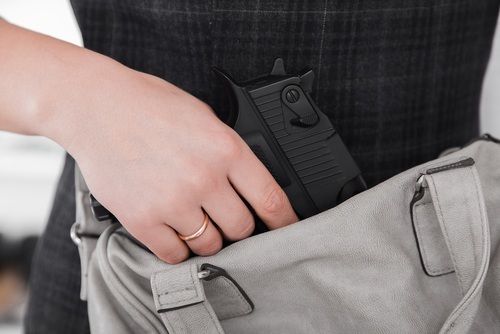 una mujer sacando una pistola de su bolso como ejemplo de agresión agravada en California 