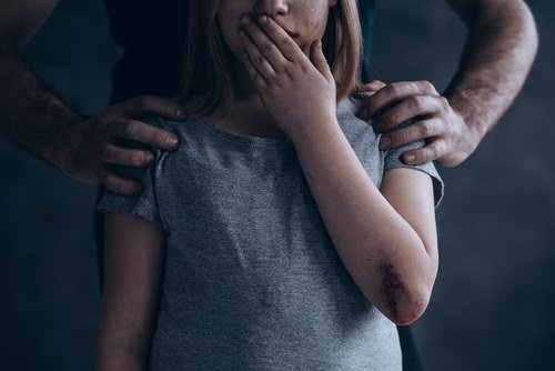 Man placing hands on shoulders of young girl to illustrate the crime of child annoyance.