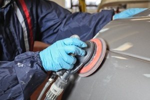 trabajador de carrocería lijando un auto recién pintado