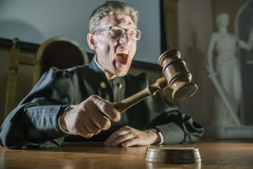 Angry judge banging a gavel as an example of contempt of court in Colorado.