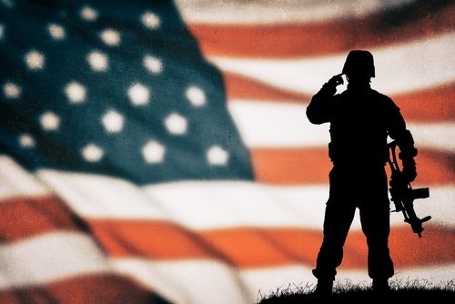 Silueta de soldado con equipo de combate de pie frente a la bandera estadounidense: la desviación militar es una opción para los veteranos en algunos casos criminales de California