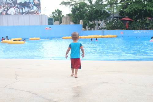 niño parado frente a una piscina