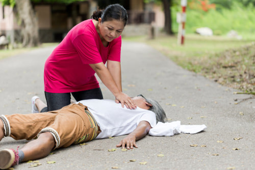 Good Samaritan administering CPR on a path.