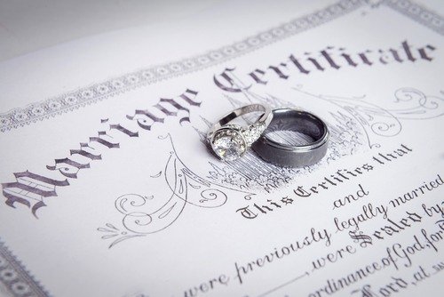 anillos de boda encima de un certificado de matrimonio