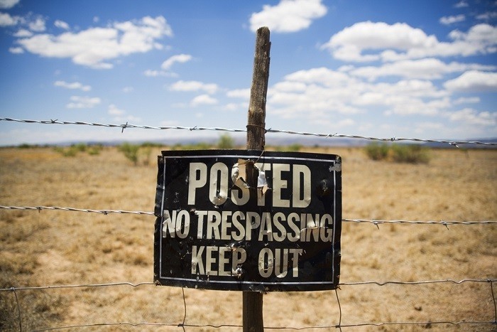 no trespassing sign hanging on barbed wire