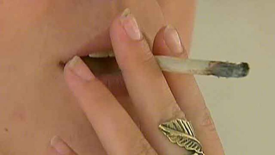 close-up of woman's hand holding a rolled joint to her mouth