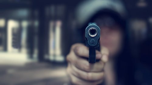 persona apuntando con un arma - Ayudar o abogar por un delito con un arma de fuego es un delito según el Código Penal 12022.4 PC