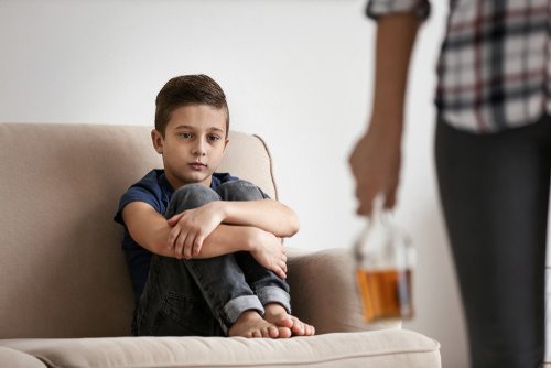 adult holding bottle of alcohol in front of child - the crime of being intoxicated in the presence of a child has been found unconstitutional