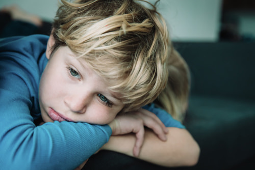 young boy resting his head on his hands after an incident of child abuse