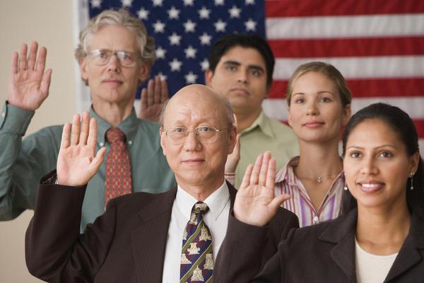 A group of immigrants raising their hands in order to take an oath of citizenship.