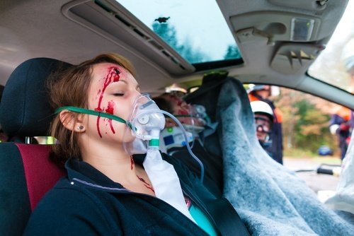 Chica con cara ensangrentada y máscara de oxígeno dentro de vehículo de emergencia
