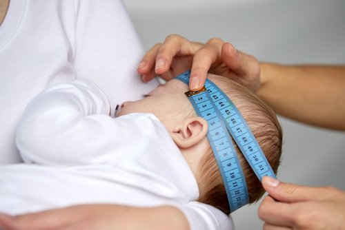 Experto médico midiendo la cabeza del bebé con una cinta métrica