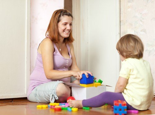 mother playing on floor with young child