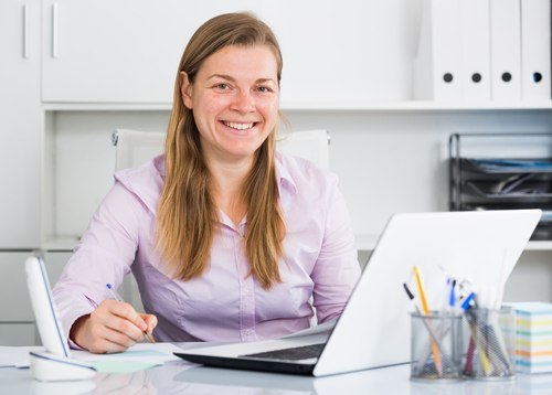 Responsible woman sitting behind computer with pen in hand. She is eligible to be a guardians.