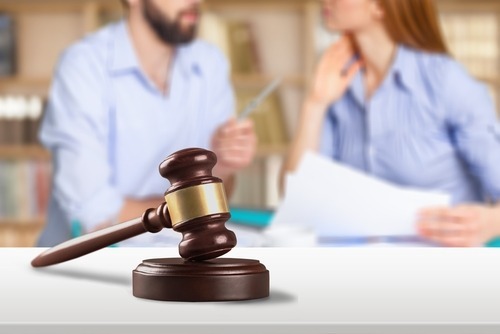 Divorcing couple looking at each other with judge's gavel in foreground.