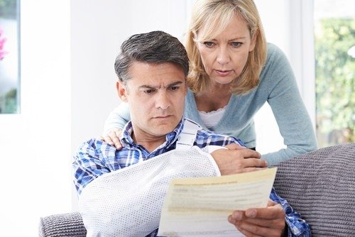 wife and husband (with arm in cast) reviewing claims document