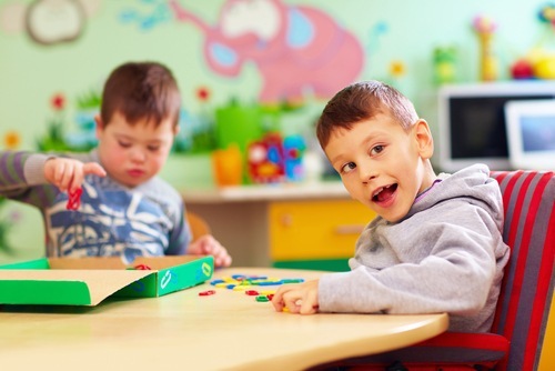 Dos lindos niños jóvenes con necesidades especiales en la escuela. Sus necesidades especiales influyen en los arreglos de pensión alimenticia de sus padres divorciados.