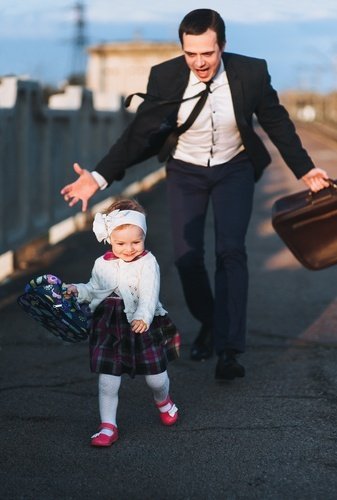 man in suit with large briefcase hurrying a young female child along