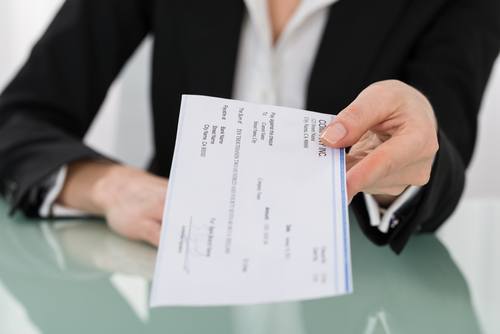 mujer de negocios en traje de la compañía de seguros de automóviles sosteniendo un cheque