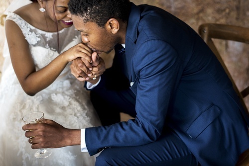Pareja afroamericana en su día de boda: el hombre besa la mano de su esposa