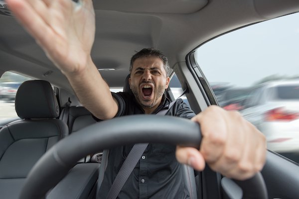 Angry man behind the wheel as an example of aggressive driving