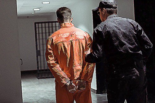 preso siendo llevado a una celda de la cárcel por un guardia