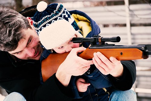 padre enseñando a su hijo cómo mirar a través del alcance