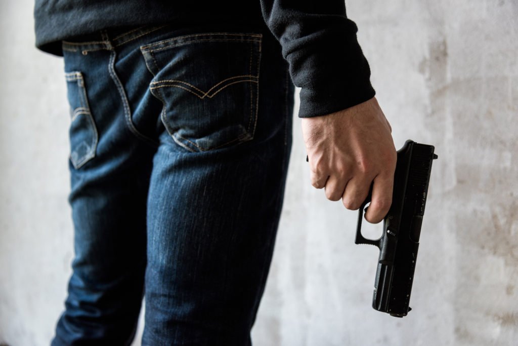 Ham sosteniendo una pistola a su lado