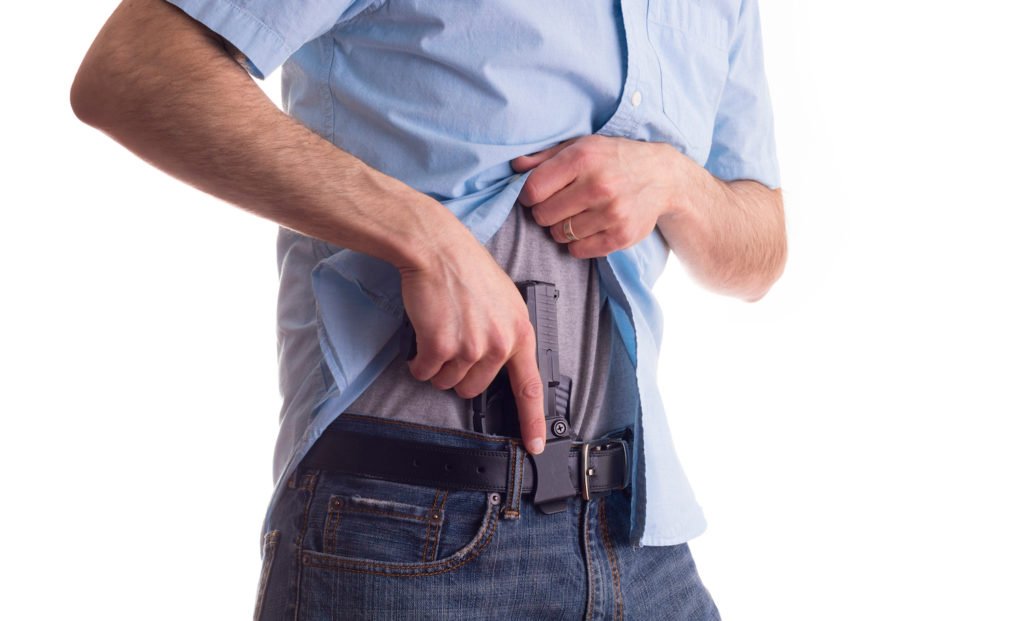 Hombre colocando pistola en su cinturón - los felones condenados están prohibidos de tener armas de fuego en Nevada según el NRS 202.360.