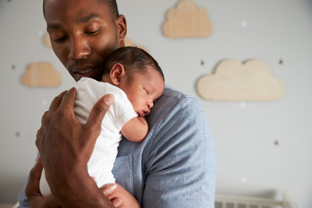 New father holding newborn during baby-bonding leave - California's New Parent Leave Act allows workers up to 12 weeks of unpaid leave for this purpose