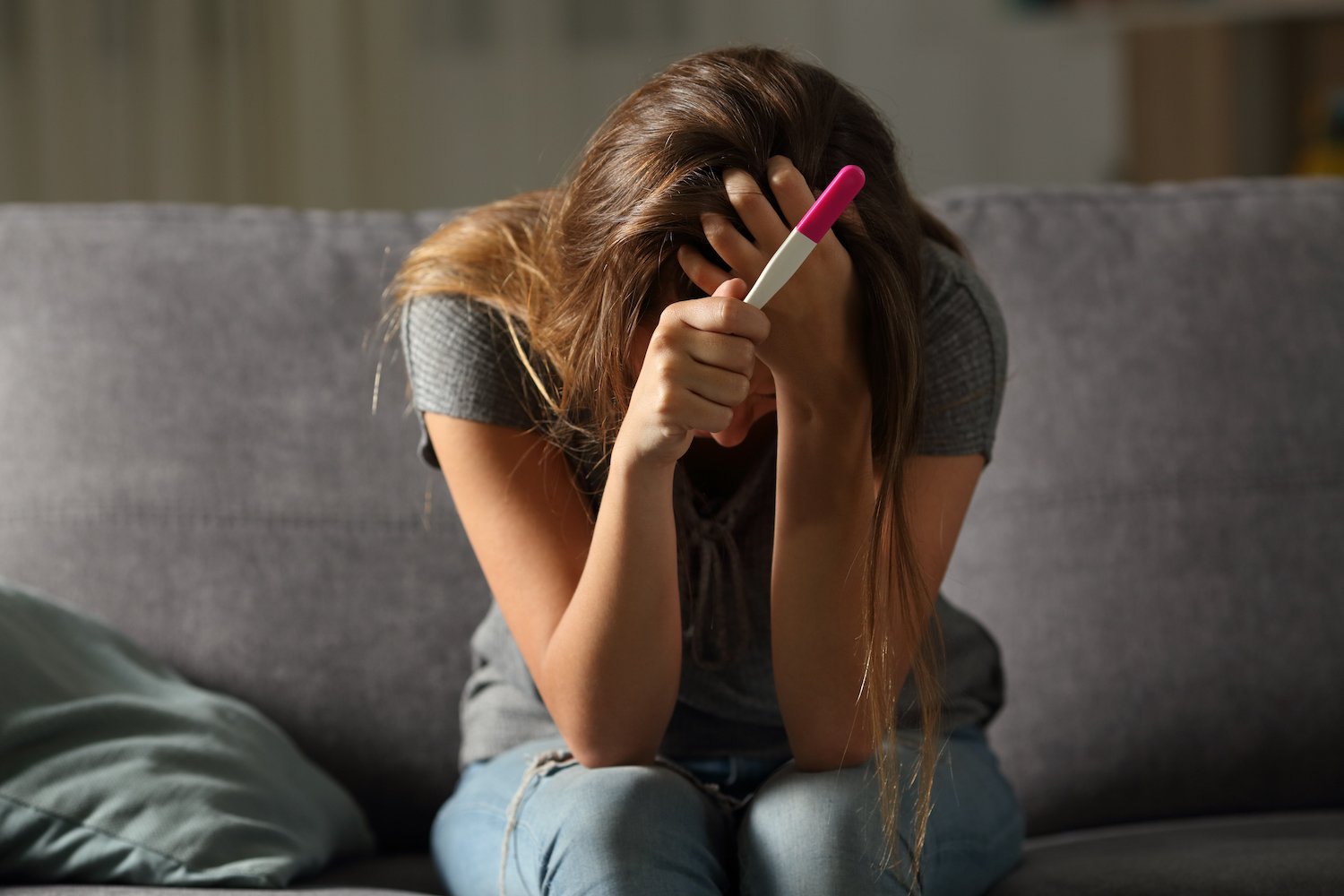 Woman holding a pregnancy test after her IUD fractured and failed.
