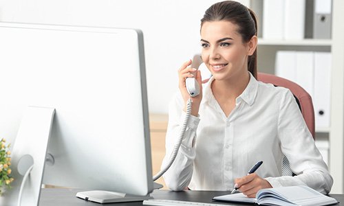 receptionist at computer speaking on phone