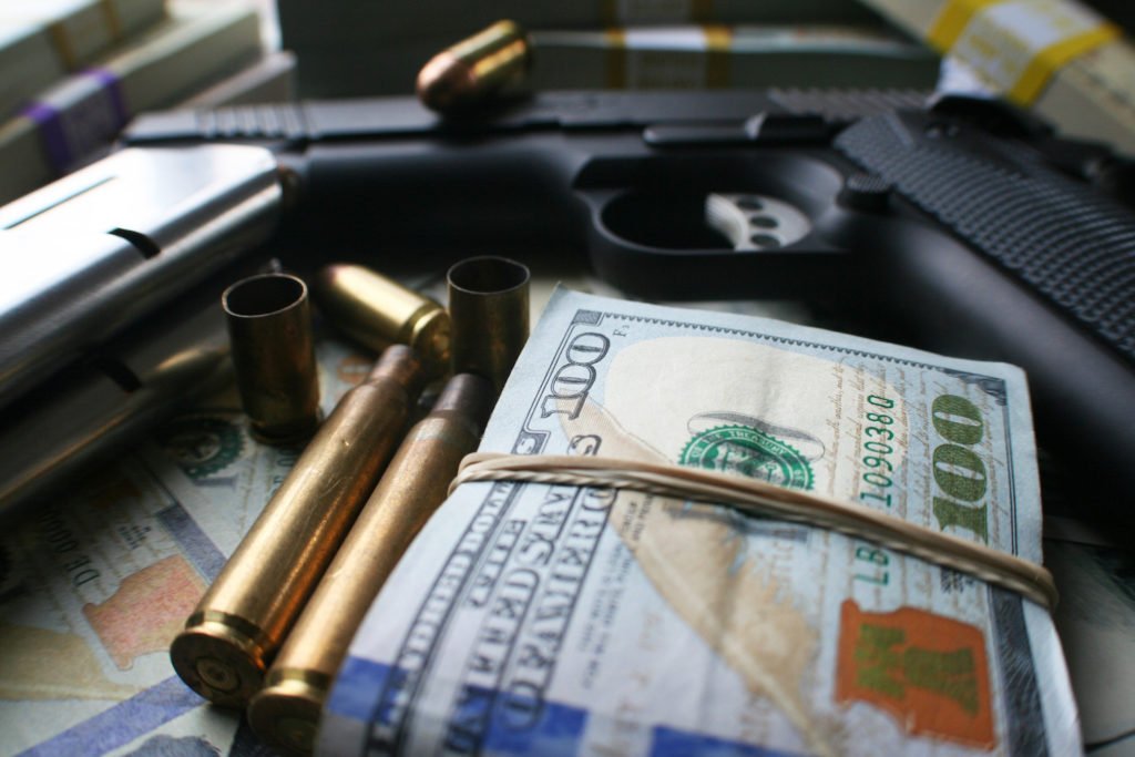 Guns, bullets, and cash to illustrate a racketeering (RICO) ring.