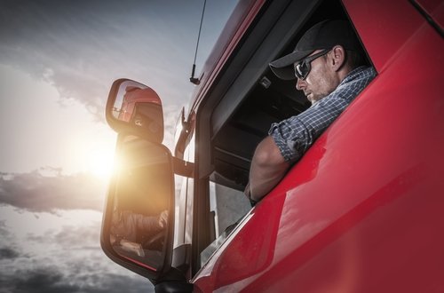 conductor de camiones mirando por la ventana de un gran camión - conducir un vehículo con exceso de peso en California puede ser un delito según el Código Penal 35551a